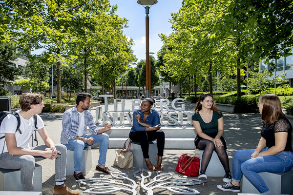 Vijf studenten zitten buiten op de campus van Tilburg University