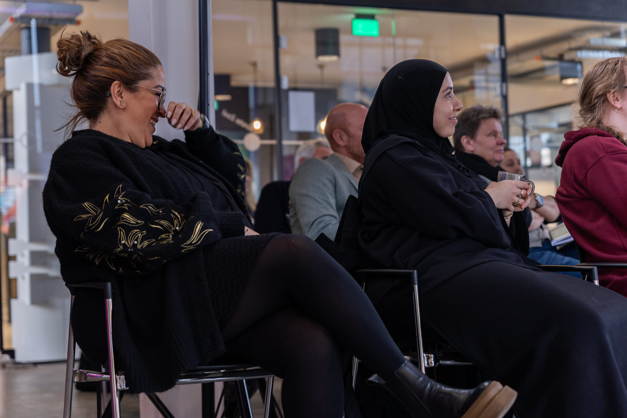 Twee vrouwen die deelnemen aan het event Bewustwording inclusief ondernemerschap, lachen in het publiek.